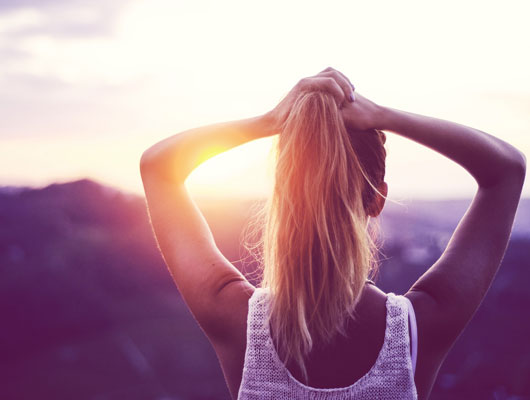 Frau genießt unbeschwert den Sonnenuntergang, frei von PMS Beschwerden