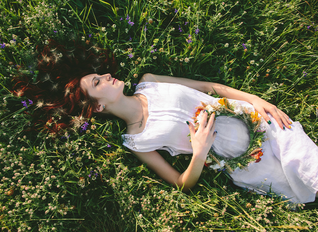 Frau liegt entspannt auf Wiese - Pflanzliche Schlaf-und Beruhigungsmittel
